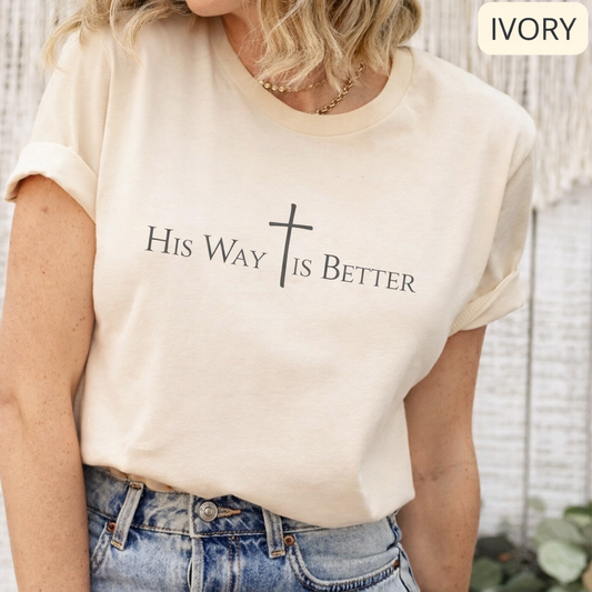 Woman wearing ivory Christian shirt with His Way Is Better text and minimalist cross design
